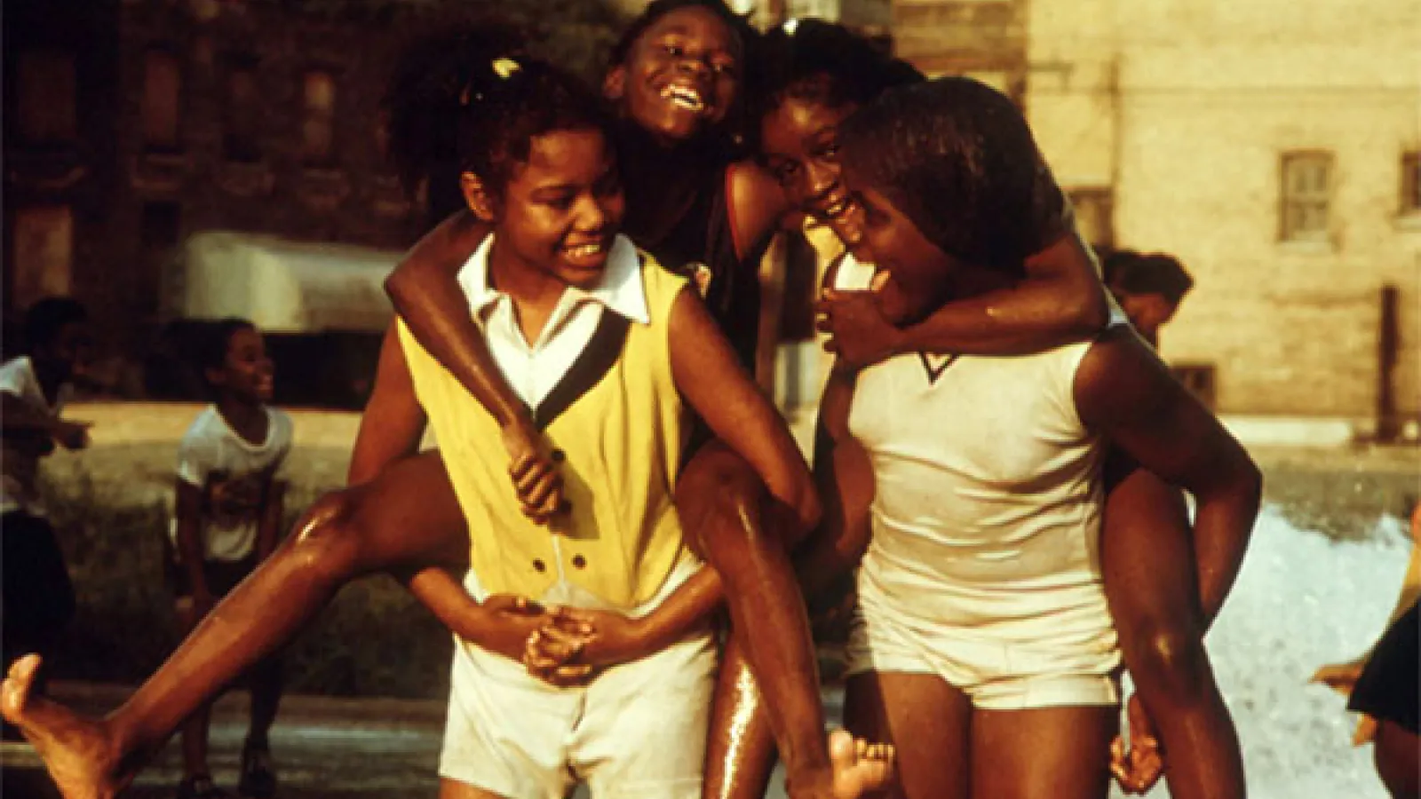 African-American children cool off with water as they play and piggy back ride each other at Woodlawn Community, Chicago, Illinois, 1973. Image courtesy John White/US National Archives. (Photo via Smith Collection/Gado/Getty Images).