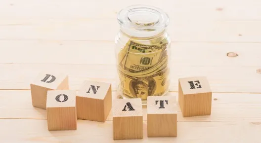 jar with bills of money in it and blocks in front of it that spell out the word donate